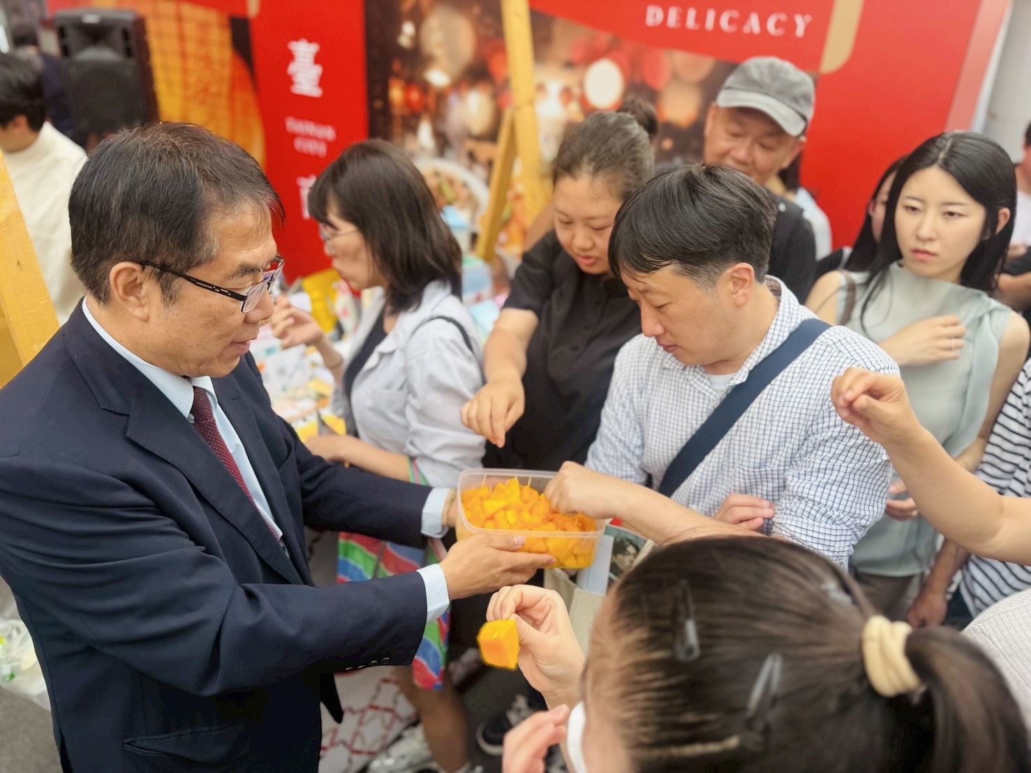 ▲市長黃偉哲出席在首爾弘大商圈的農產觀光行銷活動，現場請參與民眾試吃芒果。（圖／台南市政府提供）